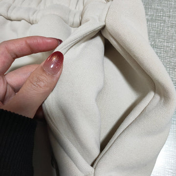 Close-up of a beige fabric with a hand holding it, on a textured gray background