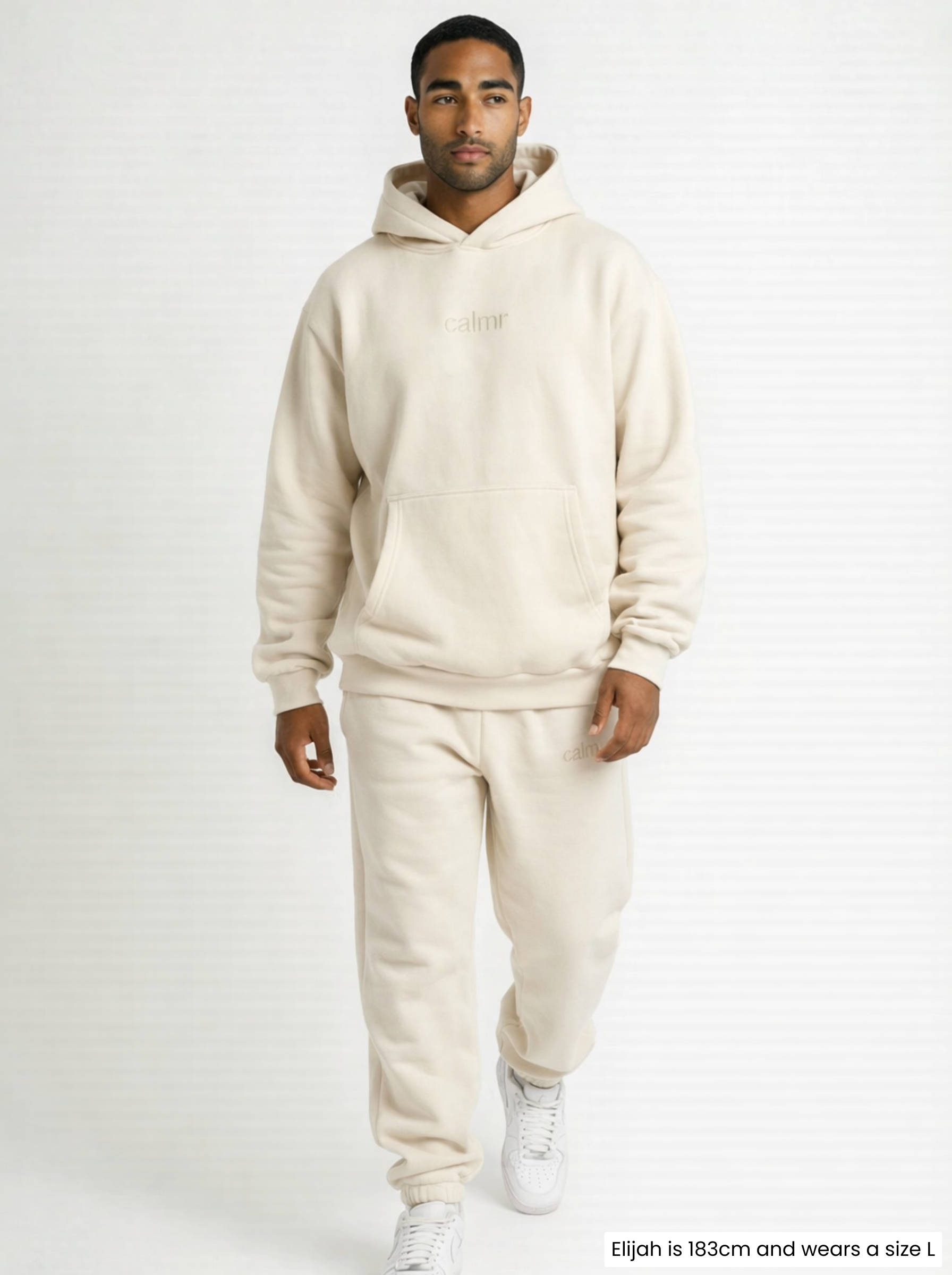 Man wearing a beige tracksuit on a white background