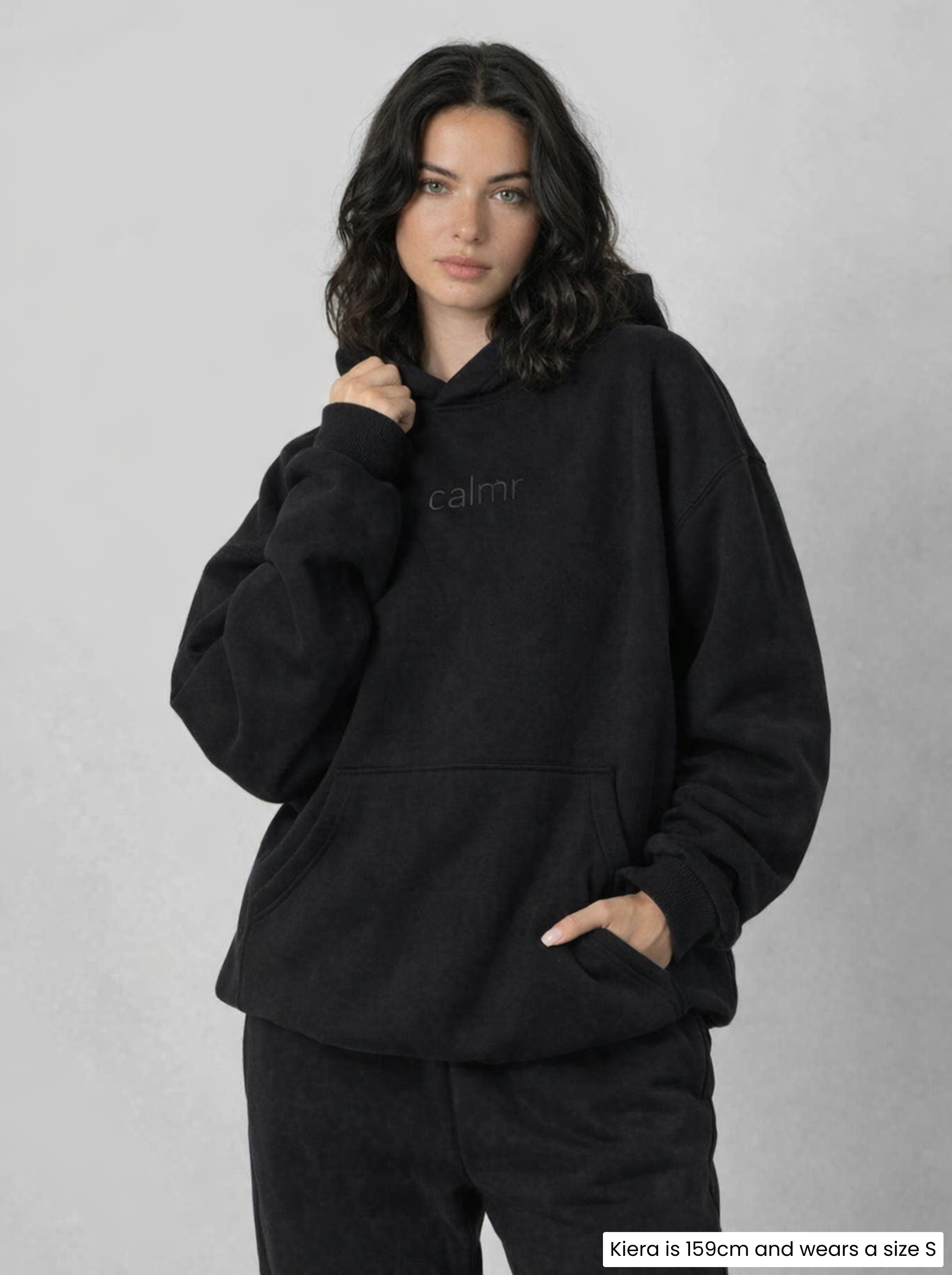 Woman wearing a black hoodie with 'Calmr' text on a gray background